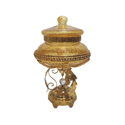 شکلات خوری مدل نگینی آبگز کد 1723 یک محصول بی‌نظیر و شیک است که با طراحی خاص و منحصر به فرد خود، جلوه‌ای لوکس و مجلل به میز پذیرایی شما می‌بخشد. این شکلات خوری از جنس فلز با روکش طلایی ساخته شده و دارای تزئینات نگینی زیبا و درخشانی است که به آن جلوه‌ای خاص و چشم‌نواز می‌دهد. درب این شکلات خوری به صورت گنبدی طراحی شده و به راحتی باز و بسته می‌شود. پایه‌های این محصول نیز با طرح‌های پیچیده و زیبا تزئین شده‌اند که به استحکام و زیبایی آن افزوده است. این شکلات خوری مناسب برای استفاده در مهمانی‌ها و مجالس رسمی و همچنین به عنوان یک هدیه لوکس و ارزشمند می‌باشد.